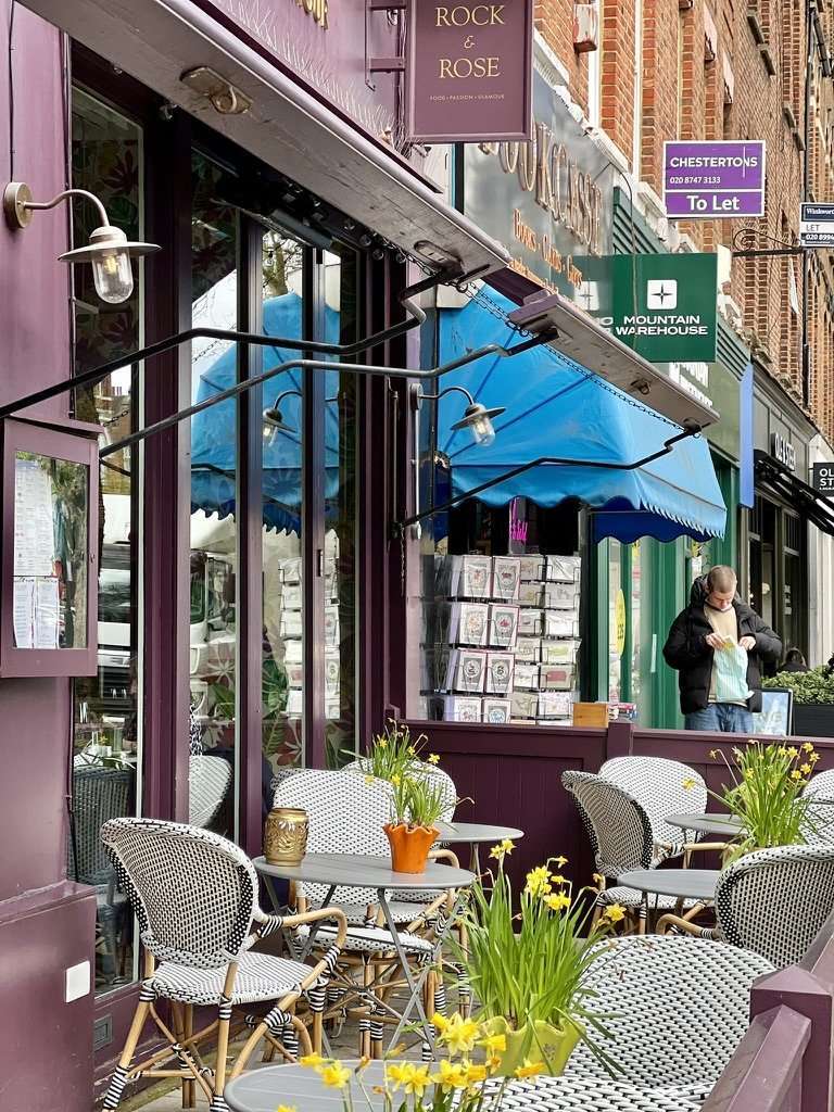 Lively and elegant Chiswick High Road lined with historic brick storefronts, independent cafes, and weekend shoppers.