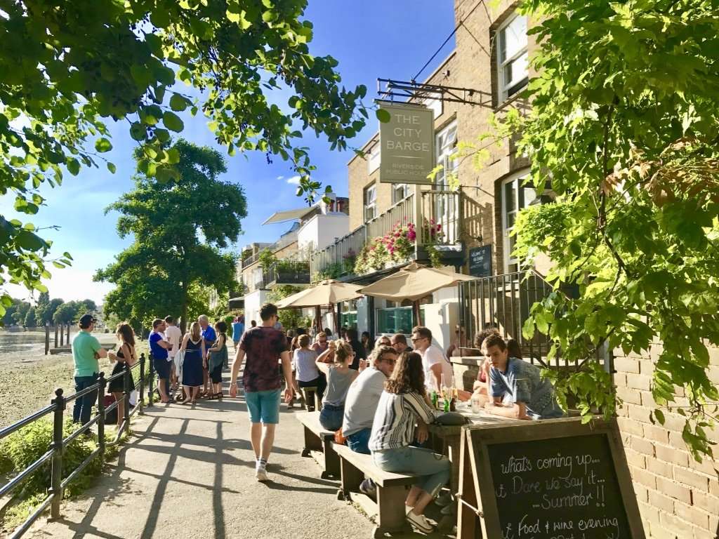 Traditional historic British pub exterior at Strand-on-the-Green with outdoor tables right on the water's edge overlooking the River Thames.
