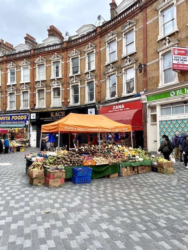 Close-up of vibrant market stalls displaying fresh tropical fruits, Caribbean vegetables, and aromatic spices in Brixton.