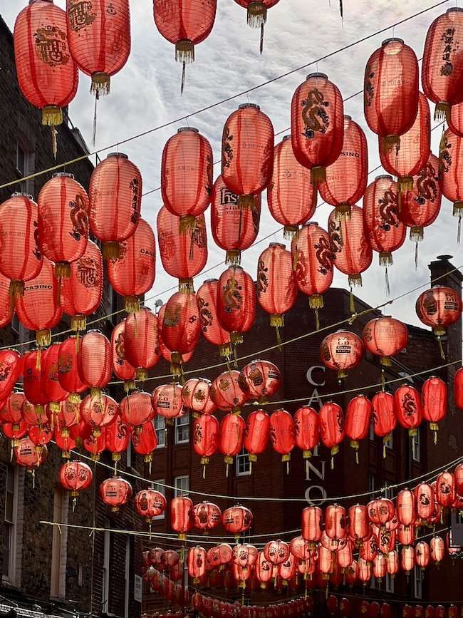 Pedestrian Gerrard Street in London's Chinatown, decorated with hundreds of traditional red paper lanterns hanging overhead.