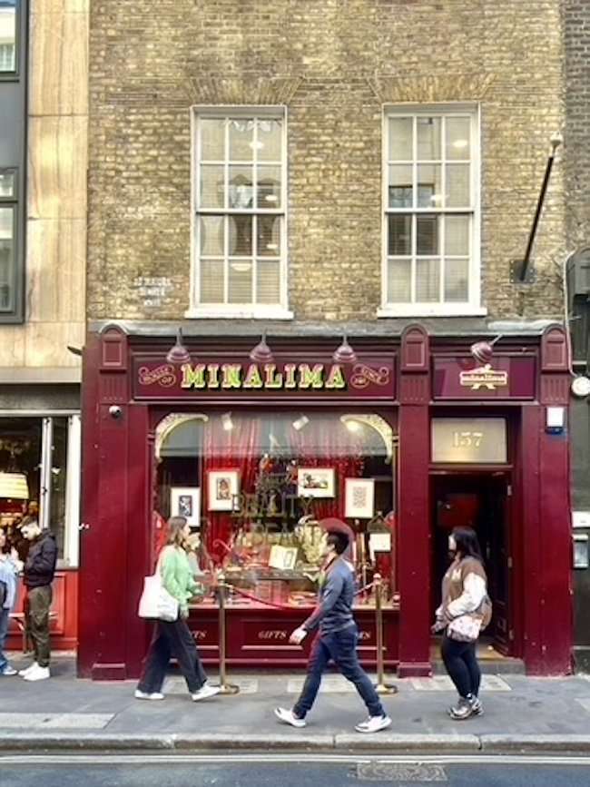 Whimsical exterior facade of the House of MinaLima store in London, decorated with vintage graphic art and magical window displays.