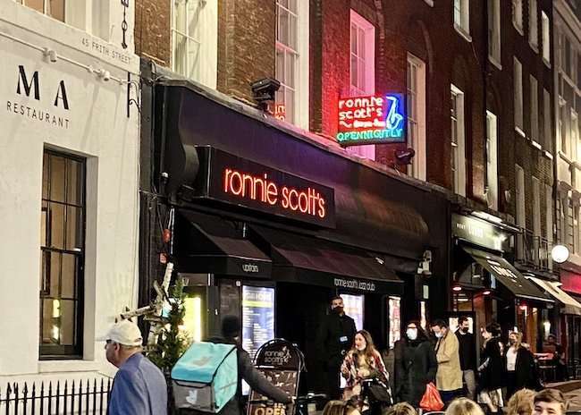London Soho Ronnie Scott's; Exterior of the famous jazz club in Soho, London, featuring glowing red lights and vintage marquee lettering.